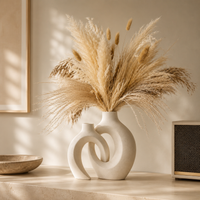 Large donut ceramic vase and small arch vase together on cream surface minimalist interior